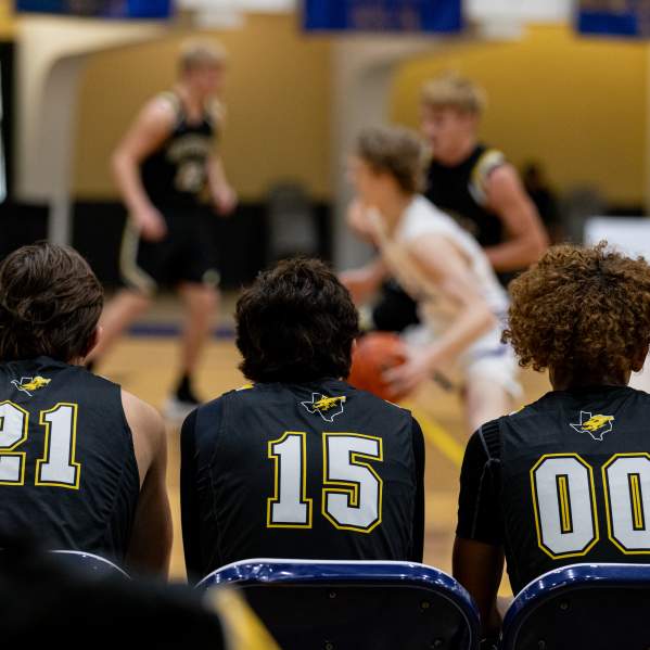 Boys Basketball tournament viewed from behind the bench onlooking the court in play.
