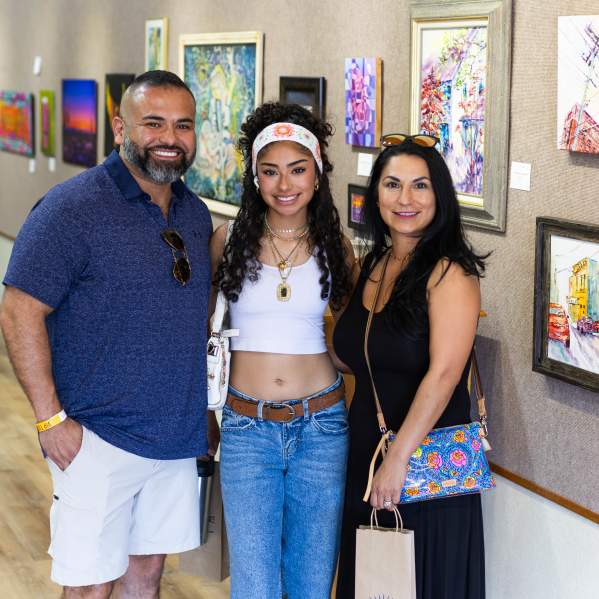 Photos of a family after checking in to Spring Art Stomp at the Brownwood Art Center featuring the gallary of art behind them on the walls.