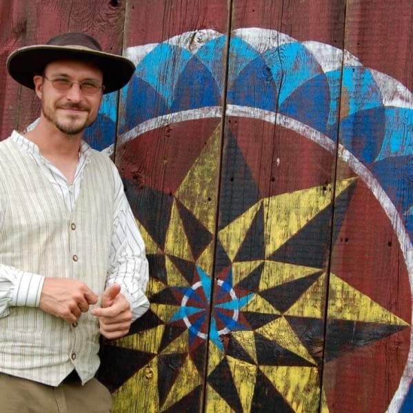 Man in front of hex symbol on a barn