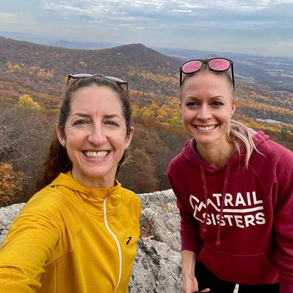 Two people smiling at the top of Hawk Mountain with the last bits of fall foliage in the background.