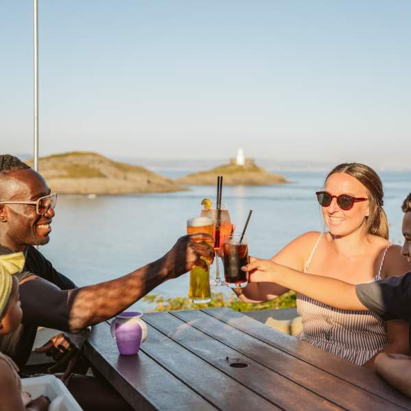 Family toasting their glasses with coast in the background