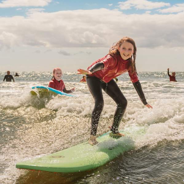 young girls surfing in rhossili bay