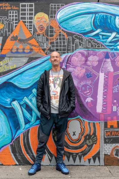 Karl, an artist, standing in front of his art