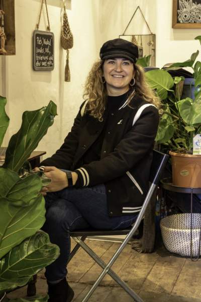 Florist sat in her shop surrounded by plants.