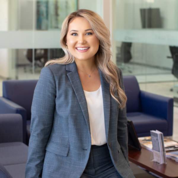 Professional headshot of a woman, with blonde hair, smiling, wearing a blue blazer/pant suit.