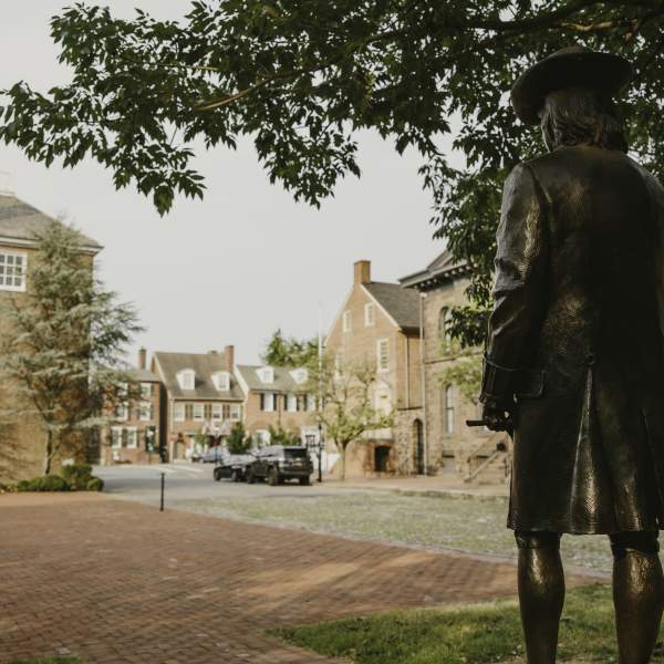 The back of a historic statue facing streets and buildings of Historic New Castle.