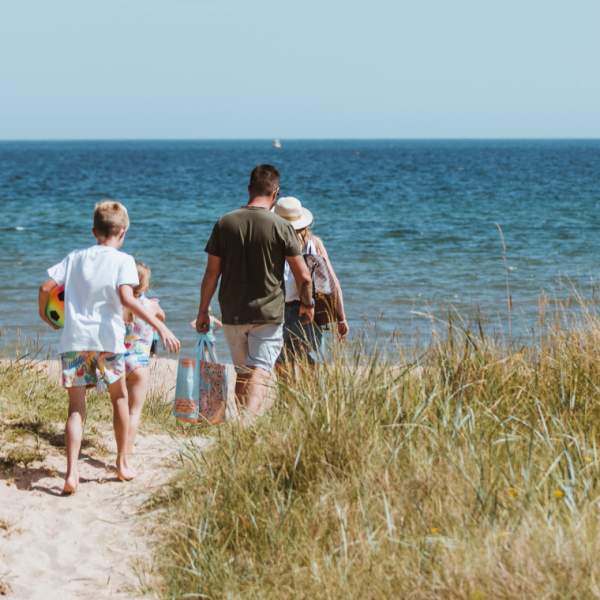 Family walking towards the sea through sand dunes at Spurn