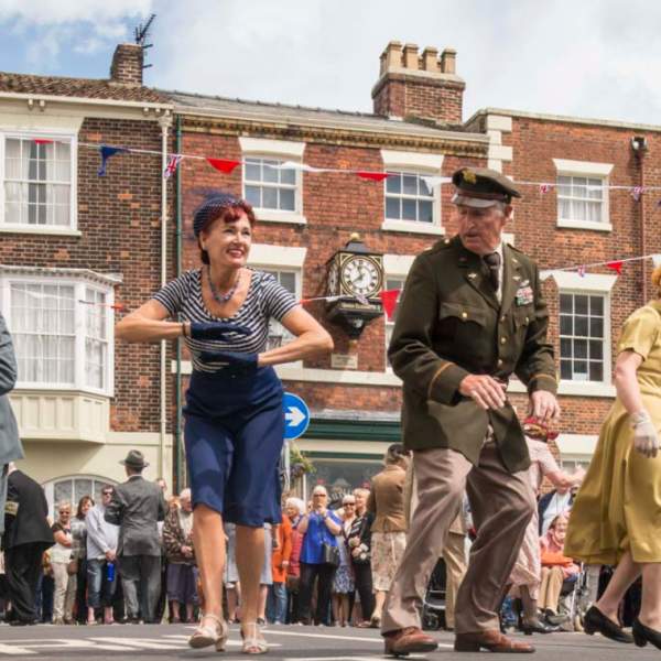 A group of dancers dressed in 1940s costume performing on stage for the 1940s and 50s summer festival in Bridlington, East Yorkshire