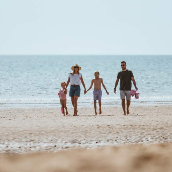 A family of four walking barefoot in the distance on the beach in Bridlington, East Yorkshire