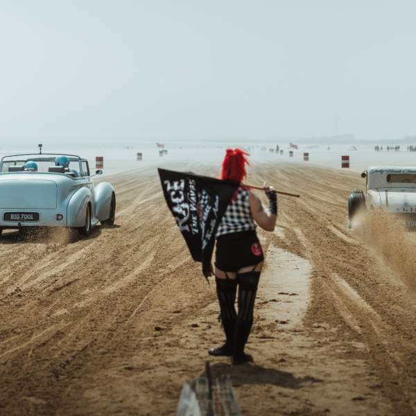 cars racing with the flag girl watching from the middle
