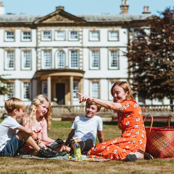 Family sat on the grass with Sewerby Hall in the background