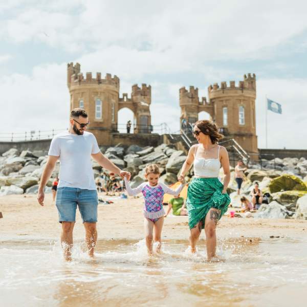 a family paddling in the sea at Withernsea Beach with the pier towers in the background.