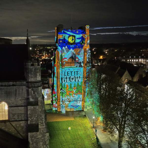 An image showing the bell tower of Chichester Cathedral lit with Christmas images for let it glow