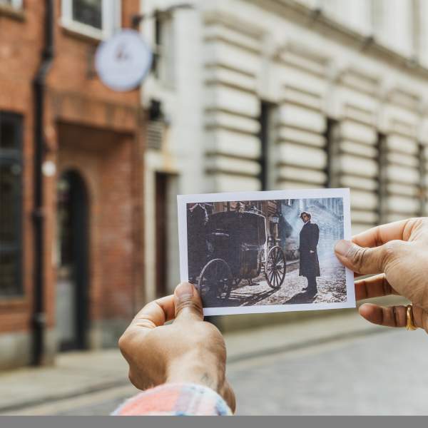 Hand holds upon a paper image of Henry Cavill in Enola Holmes 2 infront of the real building and set piece in Hull