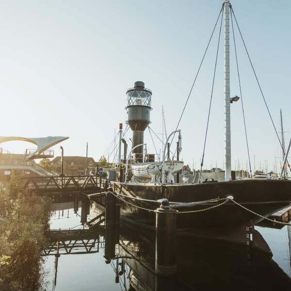 The sun sets to the left of Spurn LightShip. Murdoch connection bridge in the background and a dramatic reflection in the foreground.