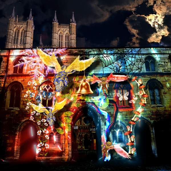 Exchequer Gate at night with a light display projected onto its front, with Lincoln Cathedral in the background