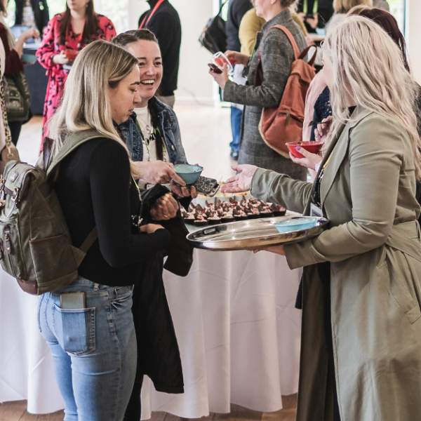 People networking at an exhibition being offered sustainable bowl food from a silver tray