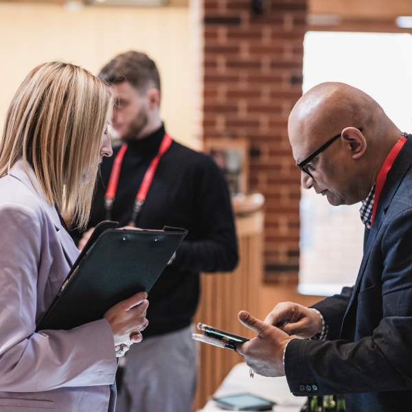 Dark skinned man e-checking in a white woman at a professional conference