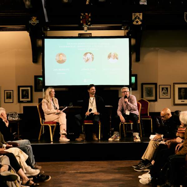 Three speakers talking to a audience at a conference in Cambridge