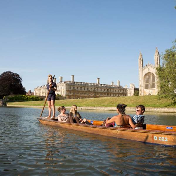 A punt boat with tourists on the River Cam with King's College Chapel in the background.