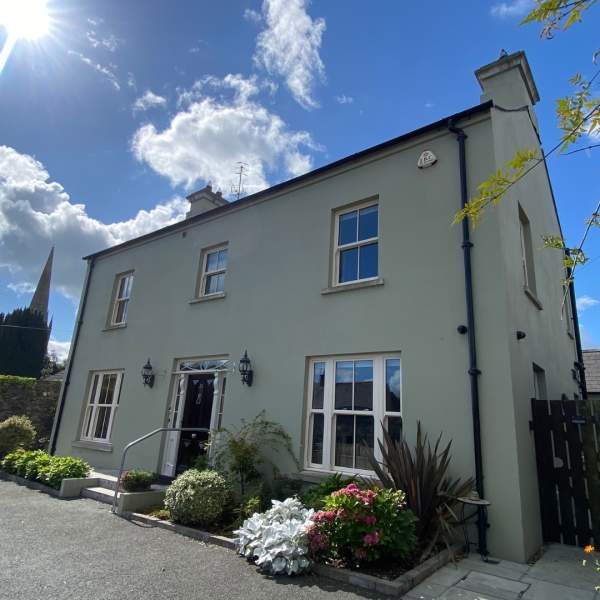 Exterior shot of Bramley House, a self-catering property in County Down.  There are plants outside the front of the house, and the sun is shining with blue skies.