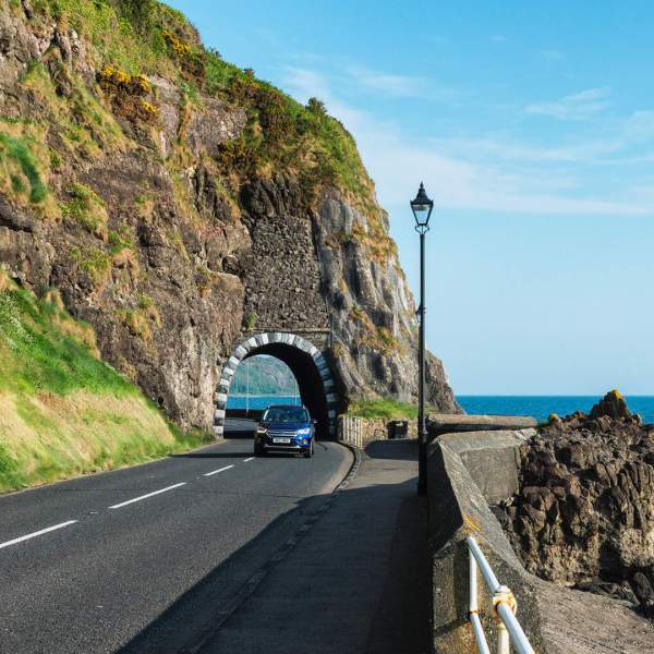 Car driving near the Black Arch on the Causeway Coastal Route