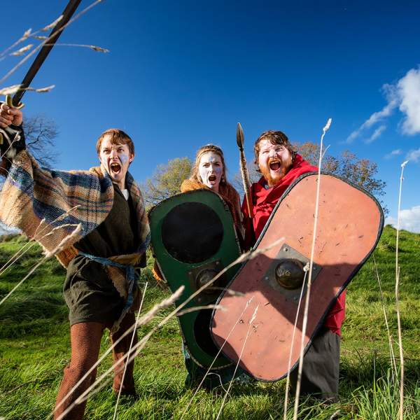 Group of three dressed up in medieval warrior costume at Navan Fort