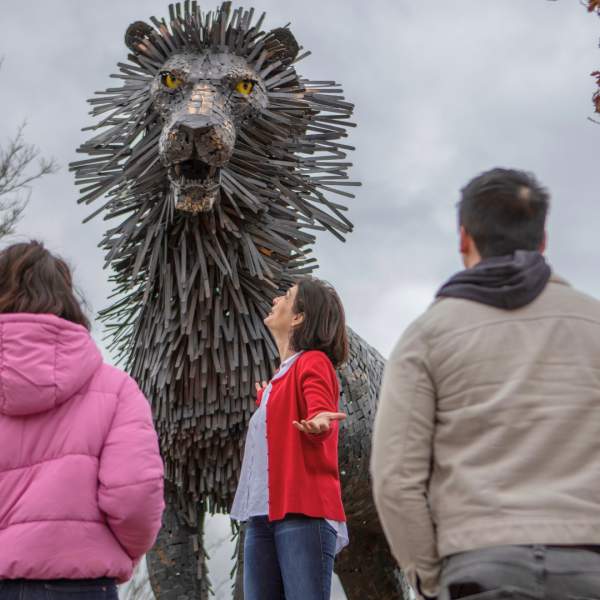A group in front of a statue of a lion 'Aslan' from the C.S. Lewis Square