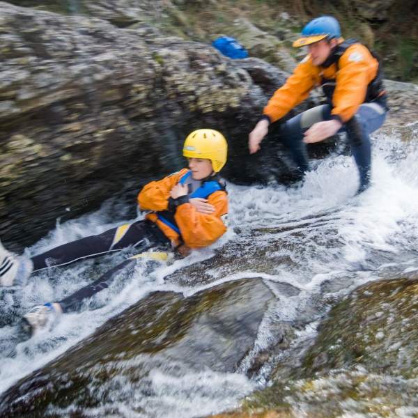 Bouldering at Bloody Bridge in Newcastle, County Down. Man slides down whitewater rocks.