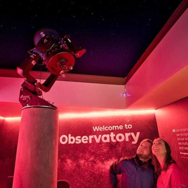 A couple looking up at a telescope at the OM Dark Sky Observatory