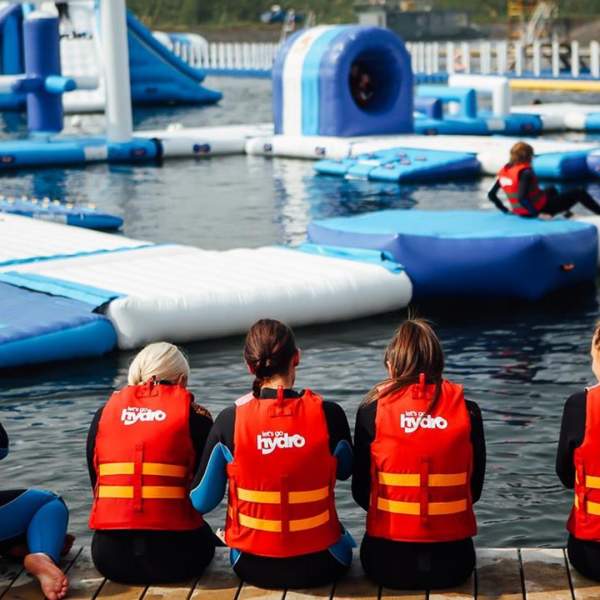 Image shows children wearing life jackets, sitting on the edge of the lake