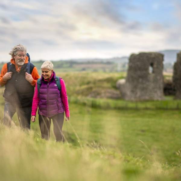 A couple enjoying a walk around the site of Harry Avery's castle with ruins in the background