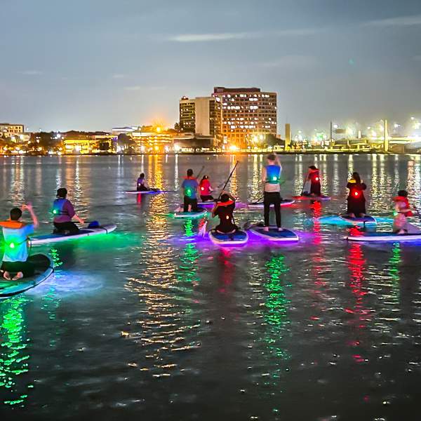 Paddleboarding at night near city with Epic Paddle Adventures