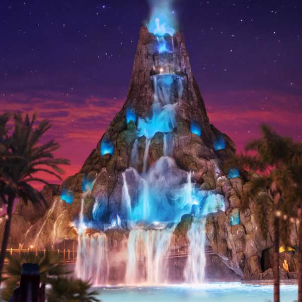 A towering volcano glows over the lagoon at night at Universal Volcano Bay Nights
