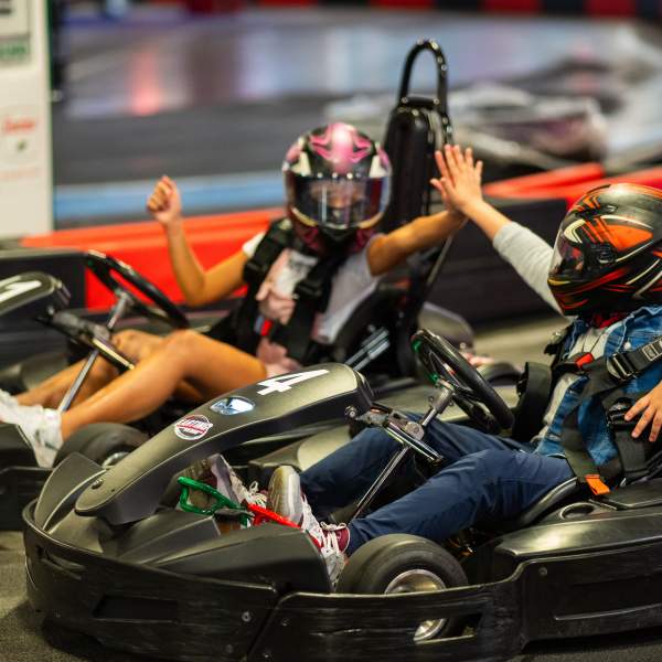 Two people high five while racing go-karts at Karting Orlando, part of Dezerland Park in the International Drive Entertainment District.