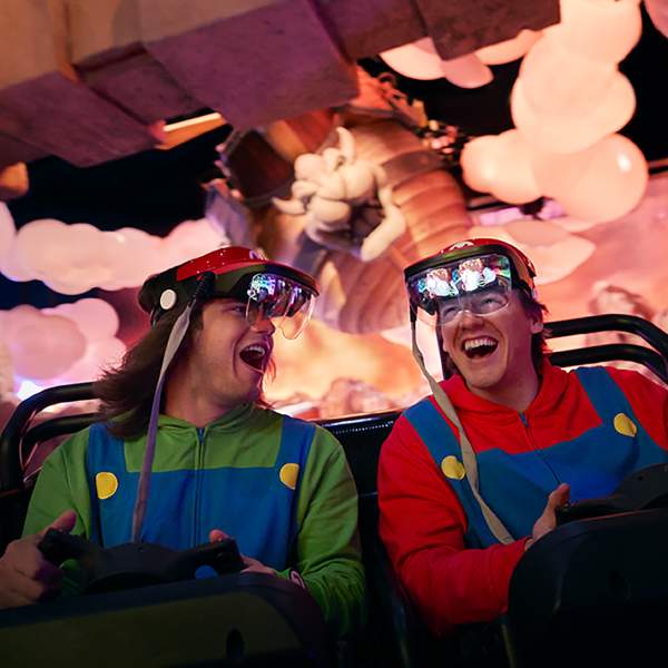 Two men laughing with joy aboard Mario Kart: Bowser's Challenge at SUPER NINTENDO WORLD, part of Universal Epic Universe in Orlando
