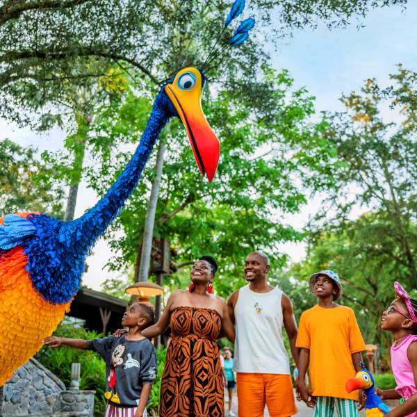 A family interacts with a Cast Member in a colorful bird costume at Disney's Animal Kingdom Theme Park, part of Walt Disney World Resort in Orlando.