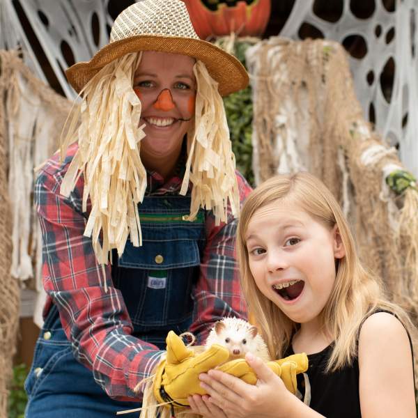 A scarecrow and young girl holding a hedgehog at Gatorland's Gators, Ghosts and Goblins Halloween event.