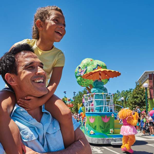 A girl sits on her father's shoulders to watch a parade in Sesame Street Land at SeaWorld Orlando