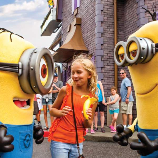 A girl holding a banana poses with two Minions at Universal Studios Florida