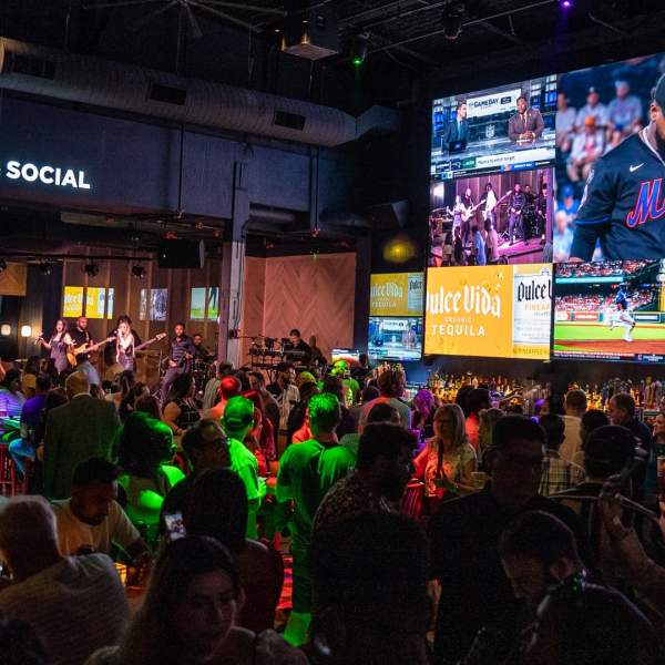 A crowd watching sports coverage on multiple big screen TVs at Sports & Social