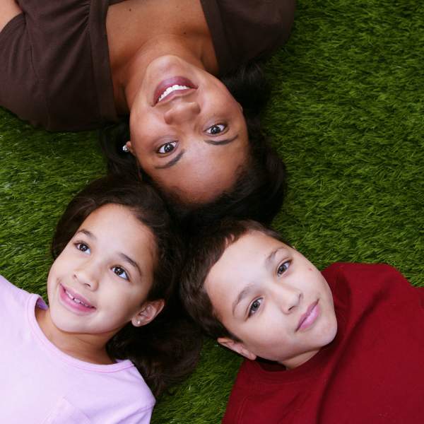 Hispanic mother and her two kids laying on the ground