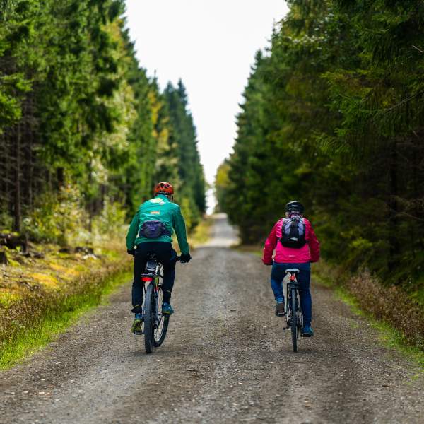 To som sykler på en grusvei i skogen