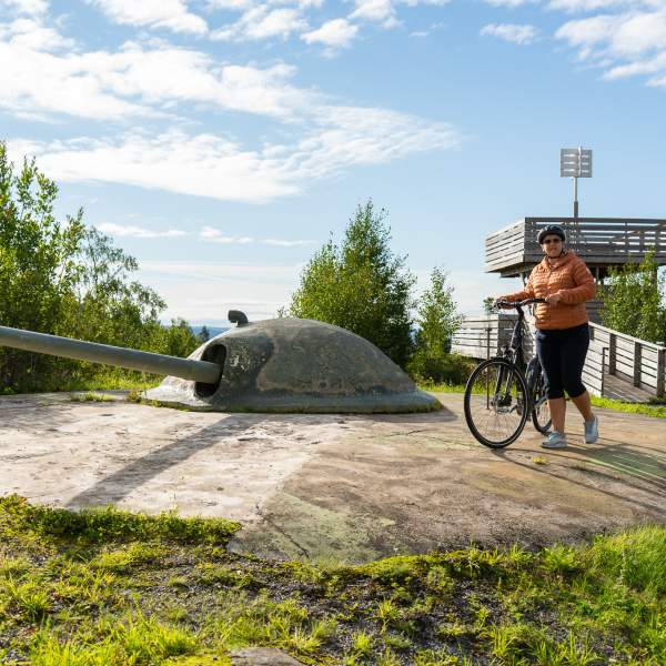 En på sykkel ved siden av en av kanonene på Trøgstad fort