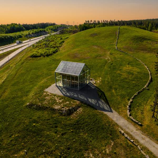 Ett gammelt hus satt inn i ett glasshus ved E18 i Knapstad