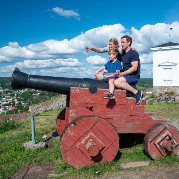 Familie som sitter på en kanon på Fredriksten festning i Halden.