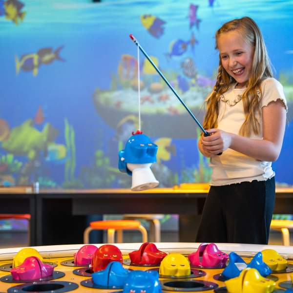 Smilende jente som tester det store fiskespillet på INSPIRIA science center