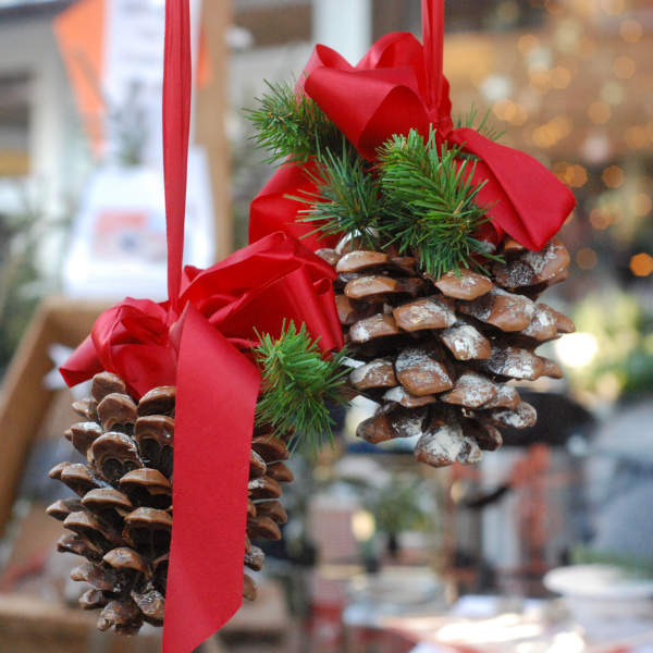 to hengende store kongler pyntet med rødt bånd og granbar