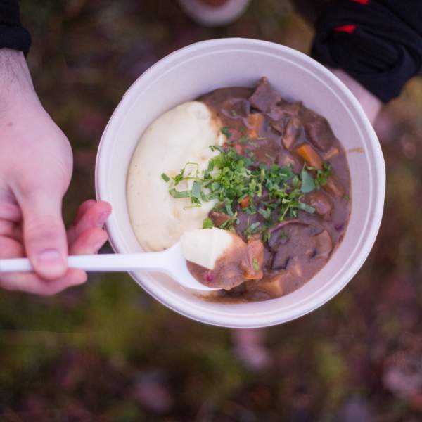 Person nyter gourmetmat i skogen.