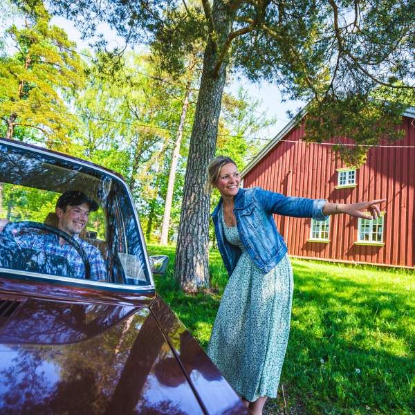 Dame peker ut veien for en bil som kommer forbi på bygdetunet